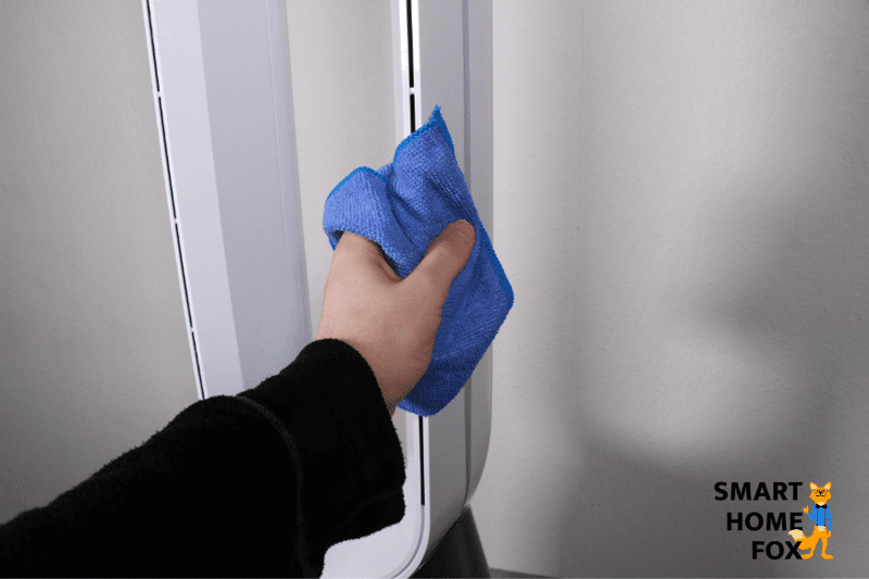 Der Turm des Dyson Pure Cool TP04 Luftreinigers wird mit einem blauen Tuch abgewischt.